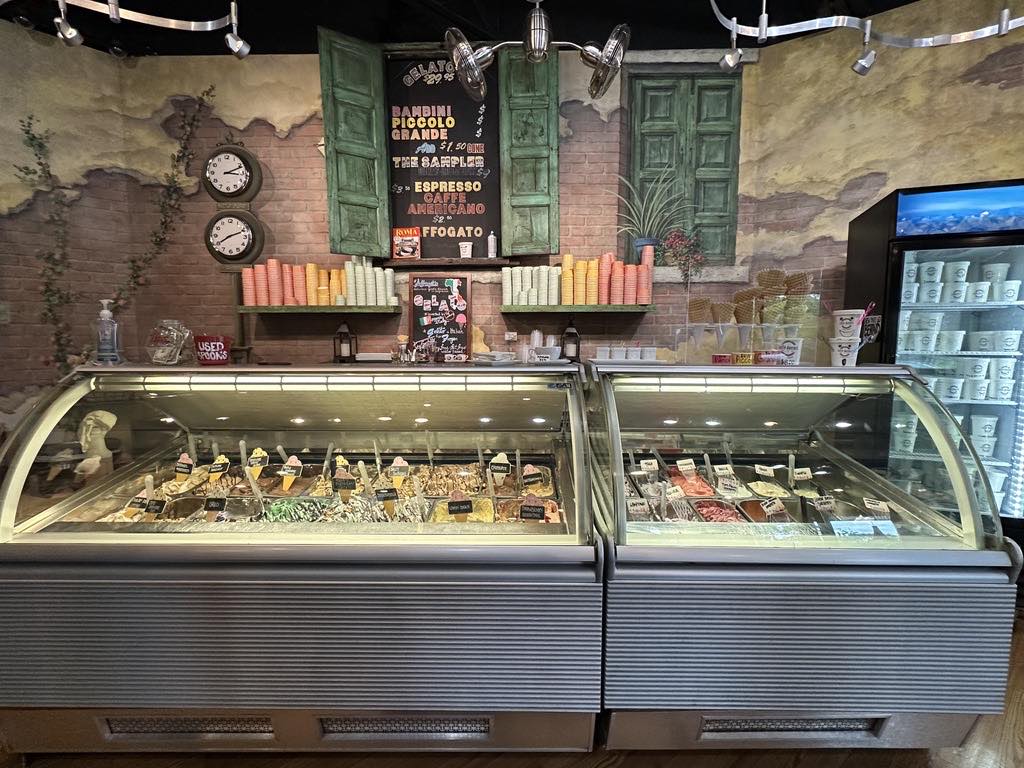 The gelato case at Caffe DaVinci lined with flavors under a hand-lettered menu board