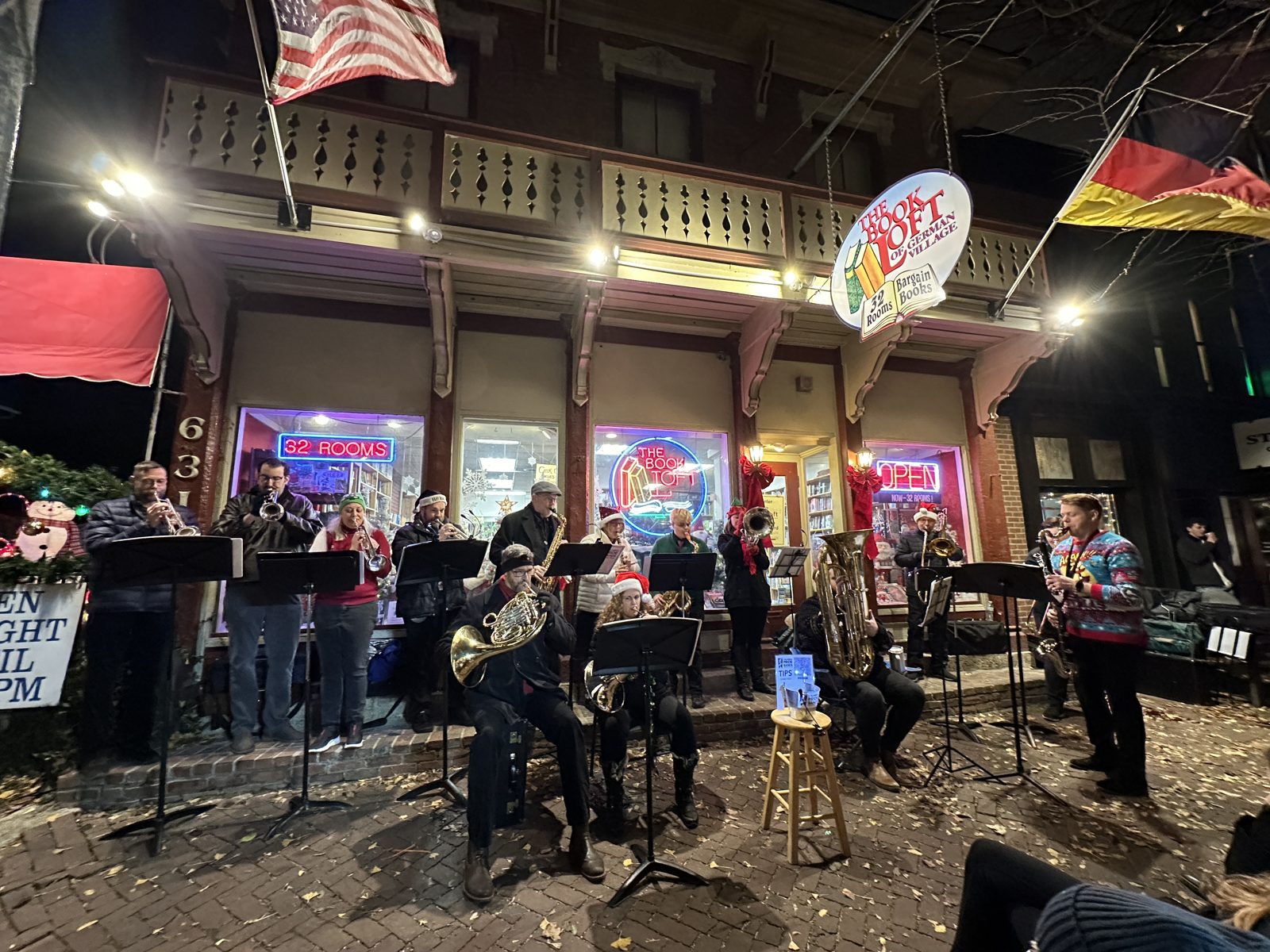 A brass band in Santa hats playing outside a lit-up shop front in German Village at night